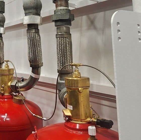 Engineered suppression cylinder bank: red tanks, brass valves, and piping