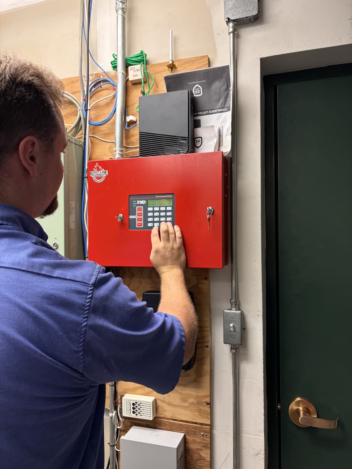 Red First-Line Fire Command Center fire alarm panel being inspected and serviced