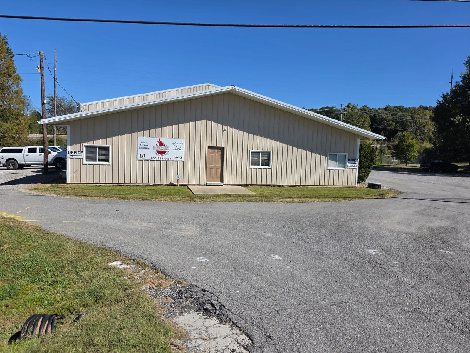 First-Line Fire Extinguisher Co. shop in Madisonville, Kentucky, with the company sign on the front wall and white pickups in the lot